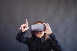 mujer feliz con fondo negro en el estudio obtiene la experiencia de usar auriculares de realidad virtual vr-glasses. foto