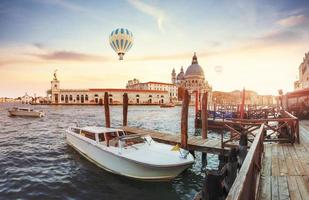 Green water channel with gondolas and colorful facades of old medieval buildings in the sun in Venice photo