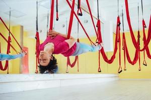 Young beautiful woman practicing yoga Fly with a hammock in the bright studio. Flying, fitness, stretch, balance, exercise. photo