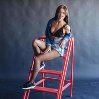 Fashionable brunette beautiful woman posing in studio wearing short jeans. photo