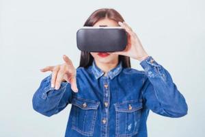 brunette beautiful woman posing in the studio, wearing jeans wear, using VR-glasses virtual reality headsets photo