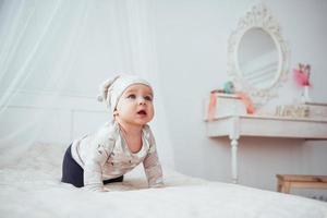 Newborn baby dressed in a suit on a soft bed in the studio. photo