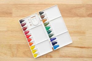 Colorful watercolor paints set in watercolor palette on wood. photo