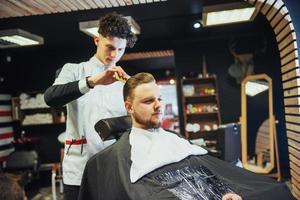 The Barber man in the process of cutting the beard of client electric clippers photo