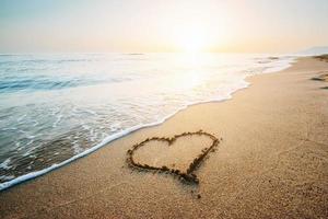 dibujando el corazón en la arena amarilla en la fantástica puesta de sol foto