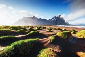 Fantastic west of the mountains and volcanic lava sand dunes on the beach Stokksness, Iceland. photo