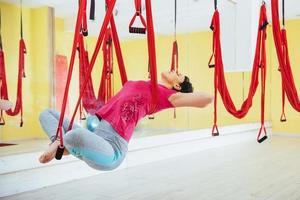 Young beautiful woman practicing yoga Fly with a hammock in the bright studio. The concept of mental and physical health. photo