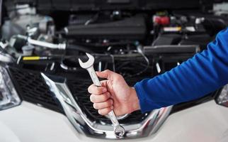 Hands of car mechanic with wrench in garage photo