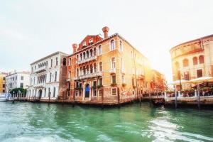 canal de agua verde con góndolas y coloridas fachadas de antiguos edificios medievales al sol en venecia, italia. foto