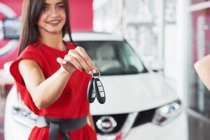 Smiling car salesman handing over your new car keys, dealership and sales concept. Happy girl the buyer photo