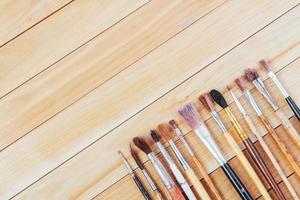 Bunch of old artist paintbrushes on wooden rustic table photo