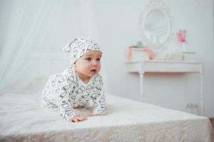 Newborn baby dressed in a suit on a soft bed in the studio. photo