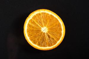 A piece of fresh orange, isolated on a black background. photo