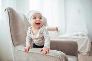 Niña de 1 año con ropa elegante, sentada en una silla vintage en la habitación. foto