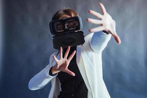 Happy woman on a black background in the studio gets the experience of using VR-glasses virtual reality headset. photo