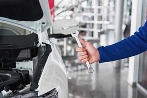 Hands of car mechanic with wrench in garage photo