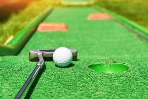 pelota de golf y palo de golf en césped artificial foto