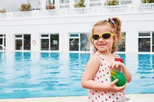 linda rubia en la piscina y sosteniendo un cóctel para niños foto