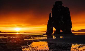 es una roca espectacular en el mar en la costa norte de islandia. las leyendas dicen que es un troll petrificado. en esta foto, hvitserkur se refleja en el agua del mar después de la puesta de sol de medianoche. foto