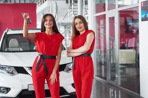 Young happy two woman near the car with keys in hand - concept of buying car. photo