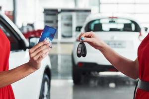 auto business, car sale, deal, gesture and people concept - close up of dealer giving key to new owner in auto show or salon photo