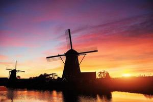 Landscape with beautiful traditional Dutch mill near water courses with fantastic sunset and reflection in water. Netherlands. photo