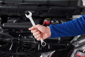 Hands of car mechanic with wrench in garage photo