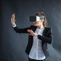 Happy woman on background in the studio gets the experience of using VR-glasses virtual reality headset photo