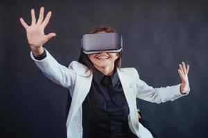 mujer feliz con fondo negro en el estudio obtiene la experiencia de usar auriculares de realidad virtual vr-glasses. foto