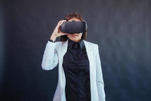 mujer feliz con fondo negro en el estudio obtiene la experiencia de usar auriculares de realidad virtual vr-glasses. foto