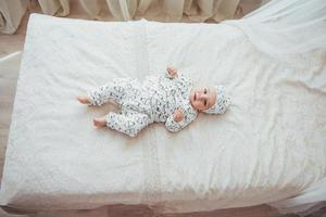 Newborn baby dressed in a suit on a soft bed in the studio. photo