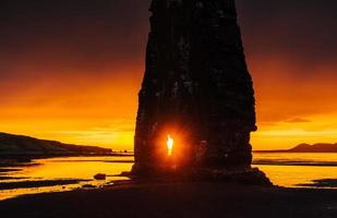 es una roca espectacular en el mar en la costa norte de islandia. las leyendas dicen que es un troll petrificado. en esta foto, hvitserkur se refleja en el agua del mar después de la puesta de sol de medianoche. foto