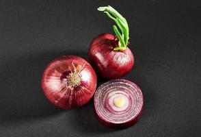 cebollas rojas enteras, aisladas en un fondo negro foto