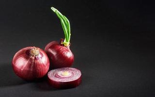 cebollas rojas enteras, aisladas en un fondo negro foto