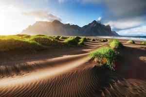 Fantastic west of the mountains and volcanic lava sand dunes on the beach Stokksness, Iceland. photo