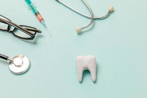 concepto de atención dental de salud. equipo de medicina estetoscopio blanco dientes sanos gafas jeringa aislado sobre fondo azul pastel instrumento dispositivo para médico dentista. día del dentista higiene bucal dental foto