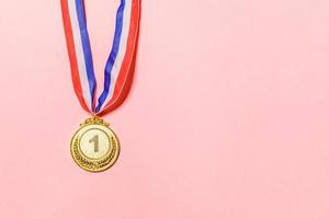 Simply flat lay design winner or champion gold trophy medal isolated on pink colorful background. Victory first place of competition. Winning or success concept. Top view copy space. photo