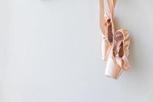 New pastel beige ballet shoes with satin ribbon isolated on white background. Ballerina classical pointe shoes for dance training. Ballet school concept, Copy space photo