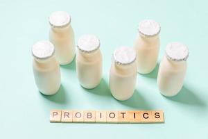 Small bottles with probiotics and prebiotics dairy drink on blue background. Production with biologically active additives. Fermentation and diet healthy food. Bio yogurt with useful microorganisms. photo