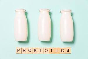 Small bottles with probiotics and prebiotics dairy drink on blue background. Production with biologically active additives. Fermentation and diet healthy food. Bio yogurt with useful microorganisms. photo