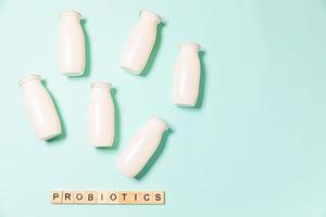 Small bottles with probiotics and prebiotics dairy drink on blue background. Production with biologically active additives. Fermentation and diet healthy food. Bio yogurt with useful microorganisms. photo