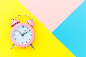 Ringing twin bell classic alarm clock isolated on blue yellow pink pastel colorful geometric background. Rest hours time of life good morning night wake up awake concept. Flat lay top view copy space. photo