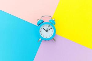 Ringing twin bell classic alarm clock isolated on blue yellow pink pastel colorful geometric background. Rest hours time of life good morning night wake up awake concept. Flat lay top view copy space. photo