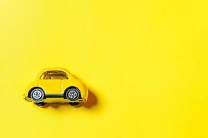 simplemente diseñe un coche de juguete retro vintage amarillo aislado sobre fondo amarillo. símbolo de automóvil y transporte. espacio de copia del concepto de entrega de tráfico de la ciudad foto