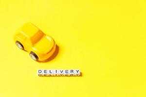 Simply design yellow toy car and inscription DELIVERY word isolated on yellow colorful background. Internet shopping online purchase e-commerce packages delivery service concept Copy space photo