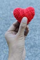 mano sosteniendo forma de corazón rojo hecha de hilo de hilo para el amor el día de san valentín foto