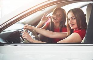 Enjoying travel. Beautiful young girl twins sitting on the front passenger seats and smiling while posing on camera photo