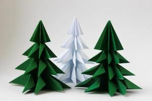 Two origami green christmas tree and white one on white background. photo