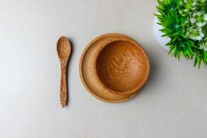 Wooden utensils on the kitchen table. Round plate, a spoon, a green plant. The concept of serving, cooking, cooking, interior details. Top view photo