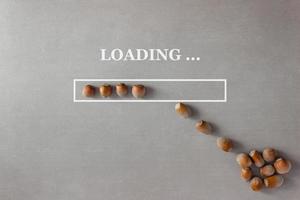 Loading background with hazelnuts in progress bar on gray background which is filled with nuts from a heap lying nearby photo